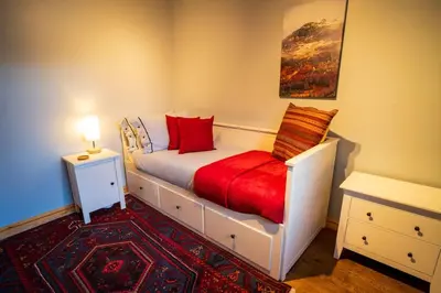 a bedroom with a white bed with red pillows at Sachsblick in Lochgoilhead