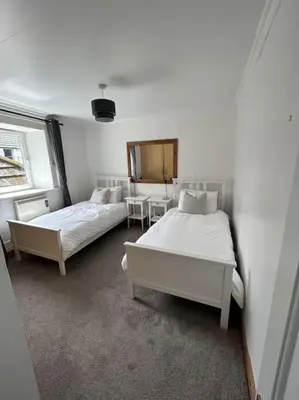 a bedroom with two beds and a table and a window at Bielding View Tarbert Loch Fyne Argyll in Tarbert
