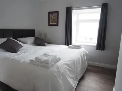 a bedroom with a white bed with towels on it at Family and dog friendly stunning barn conversion in Tarbolton