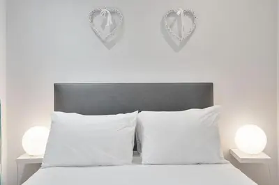 a white bed with two white pillows and two lights at Rose Street flat in Edinburgh