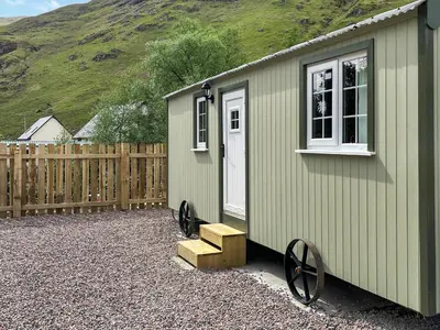 a small green building with a window and a wooden fence at Shepherds Cabin - Uk48225 in Ardgour