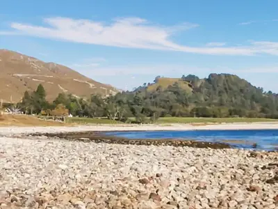 a rocky beach with mountains in the background at Shepherds Cabin - Uk48225 in Ardgour