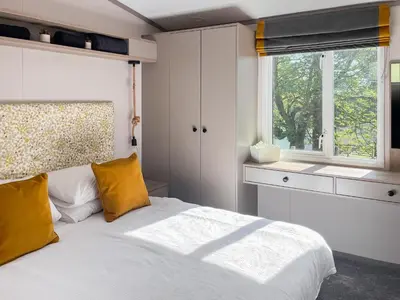 a bedroom with a bed with yellow pillows and a window at Katie's Cosy Caravan - Uk48380 in Ardgour