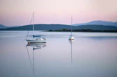 two boats are sitting in the water on a lake at Modern apartment with stunning sea views near Oban in Connel