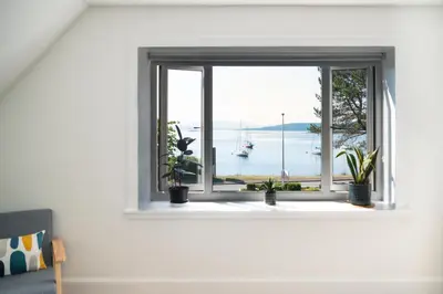 a window in a white room with potted plants at Modern apartment with stunning sea views near Oban in Connel