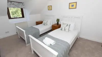 a bedroom with two beds and a window at Rowantree Cottage in Arrochar