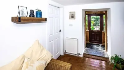 a living room with a couch in front of a door at Rowantree Cottage in Arrochar