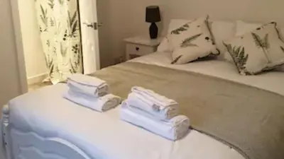 a white bed with three folded towels on it at Rowantree Cottage in Arrochar