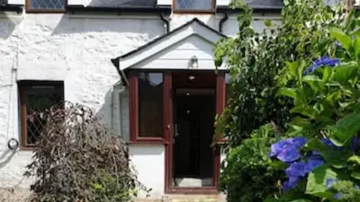 a front door of a house with purple flowers at Rowantree Cottage in Arrochar