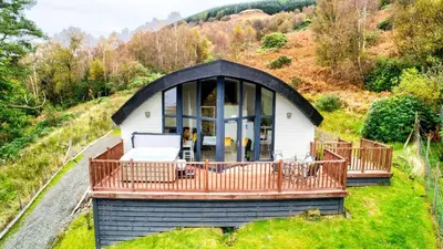 a small house on a hill with a deck at TheLodge in Arrochar