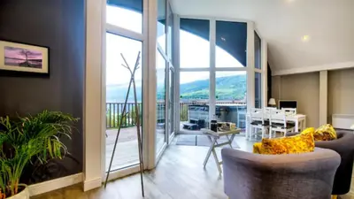 a living room with a view of a balcony at TheLodge in Arrochar