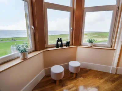 a room with three windows with a view of the ocean at Ailsa View in Girvan