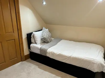 a small bedroom with a bed with white sheets and pillows at 2-Bed Cottage Sleeps 4 10 mins to Glasgow Centre in Glasgow