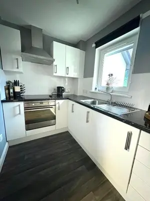 a kitchen with white cabinets and a sink and a window at View of the Isles in Largs