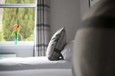 a bed with two pillows in front of a window at The Corries B&B in Luss