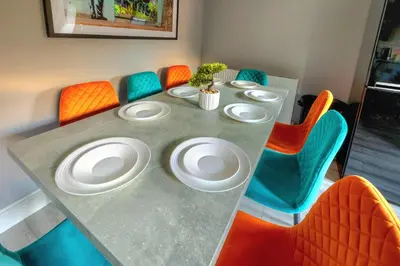 a table with four chairs and white plates on it at Cosy 4 Bedroom Home In Glasgow City - Free Parking in Glasgow