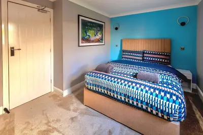 a bedroom with a bed with a blue wall at Cosy 4 Bedroom Home In Glasgow City - Free Parking in Glasgow