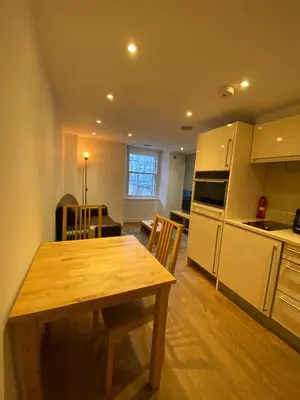 a kitchen and dining room with a wooden table and chairs at CS Exclusive Apartments of Princess Street West End in Edinburgh