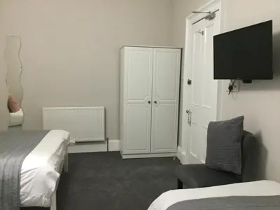 a bedroom with a bed and a chair and a cabinet at Amaryllis Guest House in Edinburgh