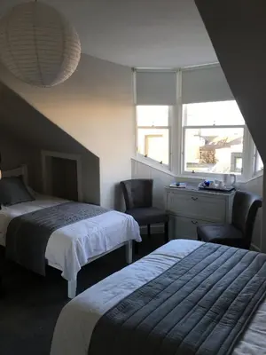 a bedroom with two beds and a desk and a window at Amaryllis Guest House in Edinburgh