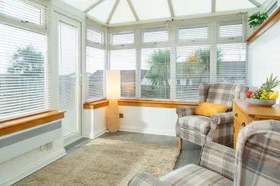 a living room with two chairs and windows at Tranquil Coastal Getaway Home in Saint Davids