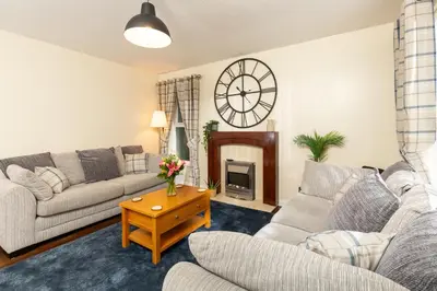 a living room with two couches and a clock on the wall at Tranquil Coastal Getaway Home in Saint Davids