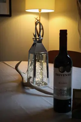 a bottle of wine and a lantern on a table at Am Tighndhuin in Killin