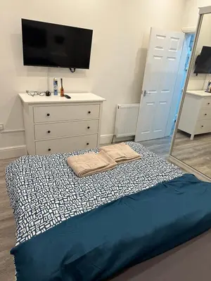 a bedroom with a bed and a dresser and a tv at Cosy Flat in Glasgow