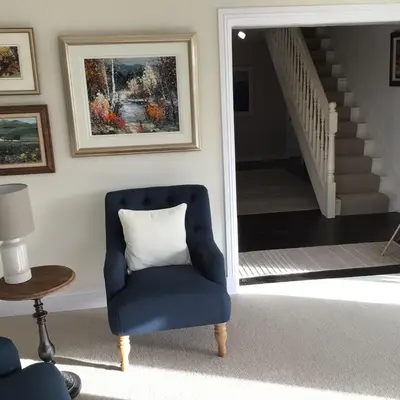 a blue chair in a living room with a staircase at Castlecroft Bed and Breakfast in Stirling