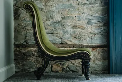 a green chair sitting in front of a stone wall at Suie Hunting Lodge in Killin