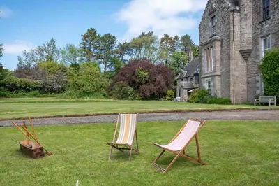 two chairs sitting in the grass in front of a building at 4 Bed in Cardross oc-t30303 in Cardross