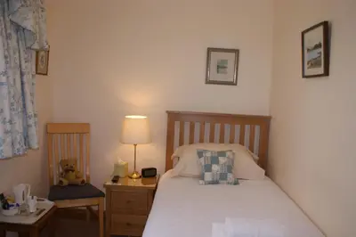 a bedroom with a bed and a table with a lamp at Greencourt Guest House in Oban
