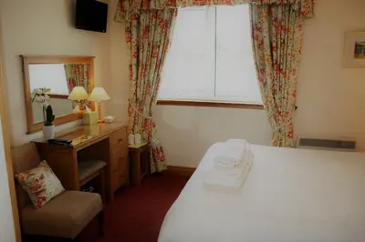a room with a bed and a desk and a window at Greencourt Guest House in Oban