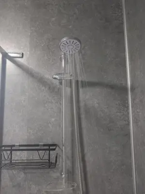 a shower with a shower head in a bathroom at Douglas Apartment - Trains to Edin & Glasgow - Private Parking in Airdrie
