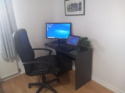 a computer desk with a laptop and a chair at Douglas Apartment - Trains to Edin & Glasgow - Private Parking in Airdrie