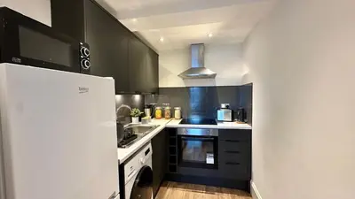 a kitchen with black cabinets and a white refrigerator at Bright and spacious apartment near Glasgow in Dalmuir
