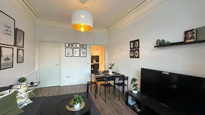 a living room with a couch and a table with chairs at Bright and spacious apartment near Glasgow in Dalmuir