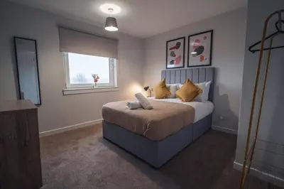 a bedroom with a bed with yellow pillows and a window at Franklin Place in East Kilbride