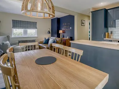 a kitchen and living room with a wooden table and chairs at Beautiful Cottage in Historical Robert Burns Farm - Pass the Keys in Dumfries