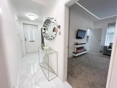 a white hallway with a mirror and a living room at Stylish Modern Glasgow Home with Excellent Value in Glasgow