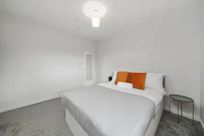 a white bed with orange pillows in a white room at BridgeCity Hidden Gem in the heart of Falkirk Roughland house Stirlingshire in Carron