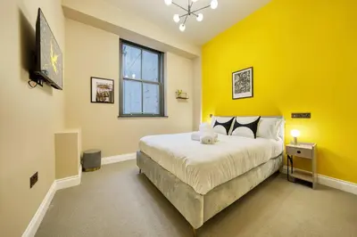 a bedroom with a large bed with a yellow wall at Grand Central Station 2 Bed Apartment A1 in Glasgow