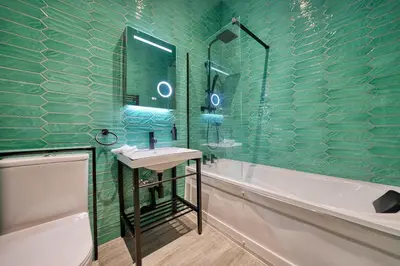 a green bathroom with a sink and a bath tub at Grand Central Station 2 Bed Apartment A1 in Glasgow