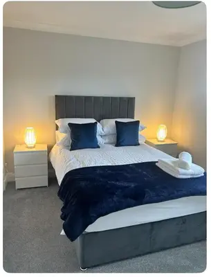 a bedroom with a large bed with blue pillows at Modern staycation Apartment in Caldercruix