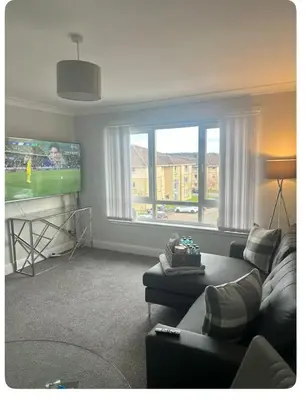 a living room with a couch and a flat screen tv at Modern staycation Apartment in Caldercruix