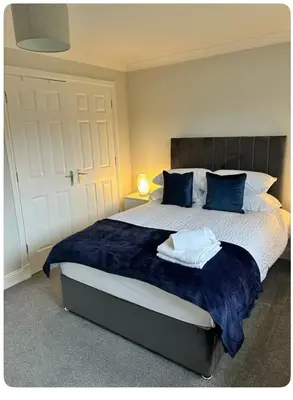 a bedroom with a large bed with blue pillows at Modern staycation Apartment in Caldercruix
