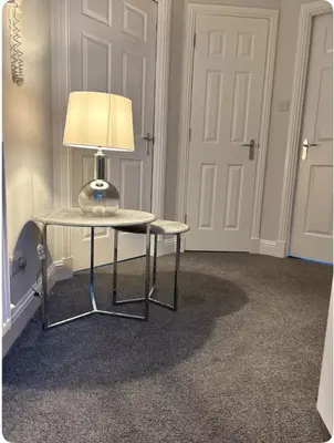 a lamp sitting on a table in a room with a door at Modern staycation Apartment in Caldercruix