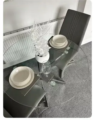 a glass table with two chairs and plates and a vase at Modern staycation Apartment in Caldercruix