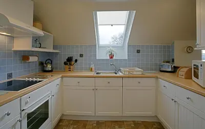 a kitchen with white cabinets and a sink and a window at Loaninghead Holidays in Drymen