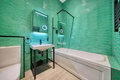 a green tiled bathroom with a tub and a sink at Stunning Central Station 2 Bed Apartment B4 in Glasgow